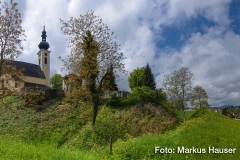 Der Kirchberg in Attersee, hier wird die karolingische Pfalz, der Königshof Atarhova, vermutet. Rechts der Buchberg, auf dessen Plateau sich eine Ringwallanlage befindet.