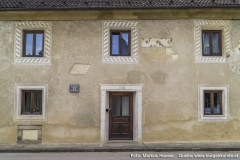 An der Südseite finden sich die 1942 wiederentdeckten Besonderheiten wie Sonnenuhr, Hausspruch und die mit "laufenden Hund" umrahmten Fenster.