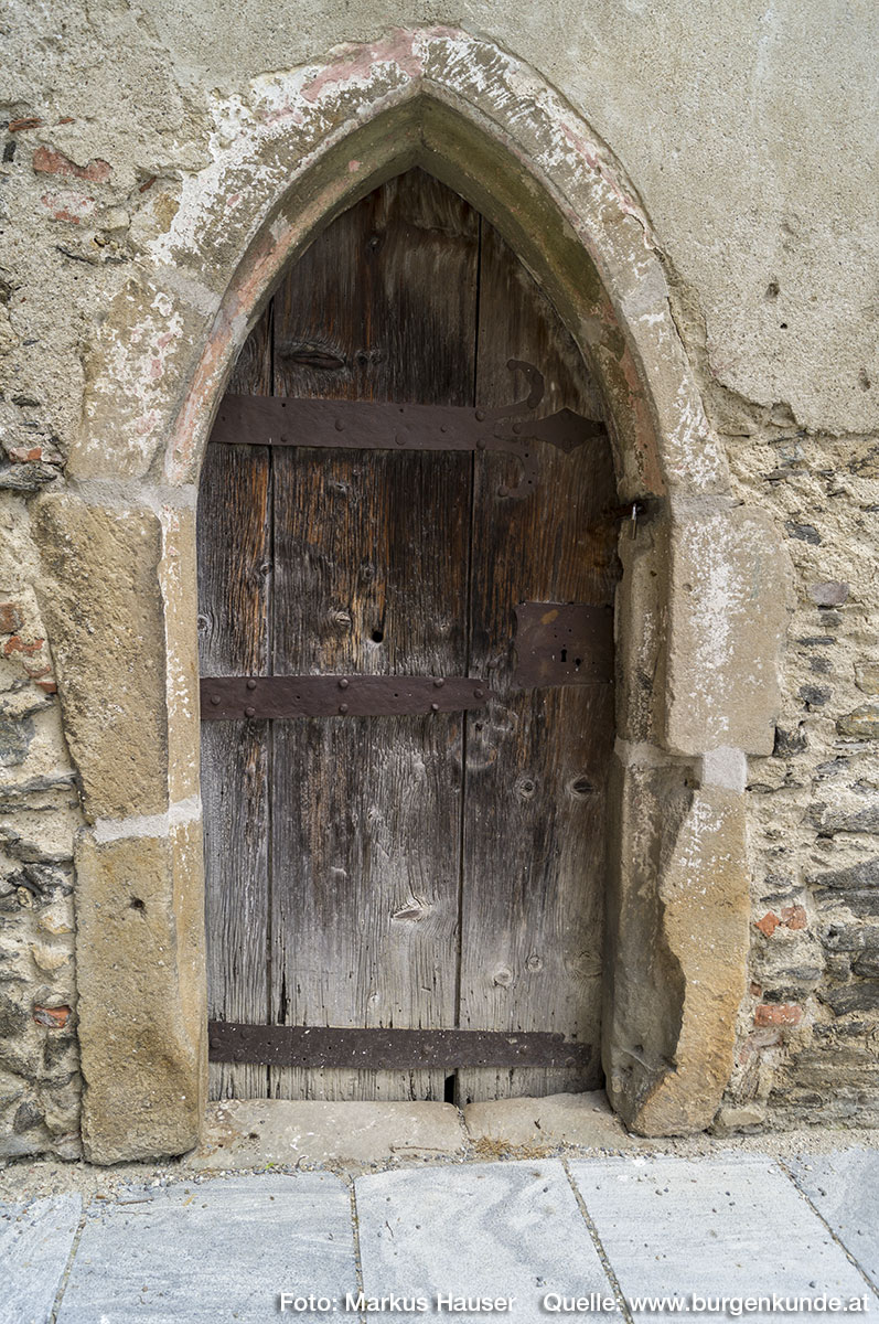 Der Zugang zur Kapelle mit Beinhaus und Karner erfolgt durch diese gotische kleine Tür, dessen spitzbogige Umrandung noch Reste von weißer und roter Bemalung zeigt.